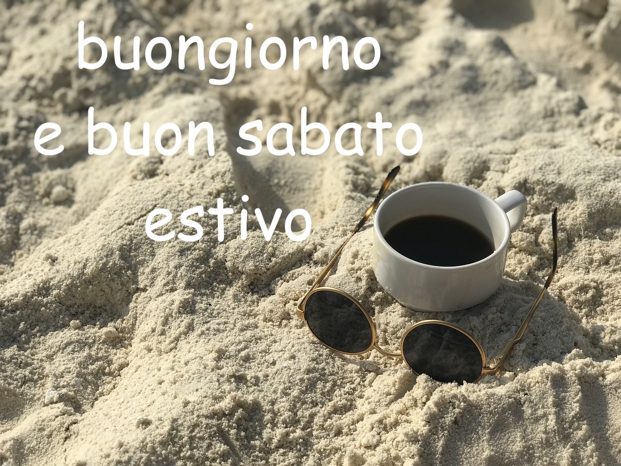 un paio di occhiali e una tazza di caffè sulla sabbia di una spiaggia estiva
